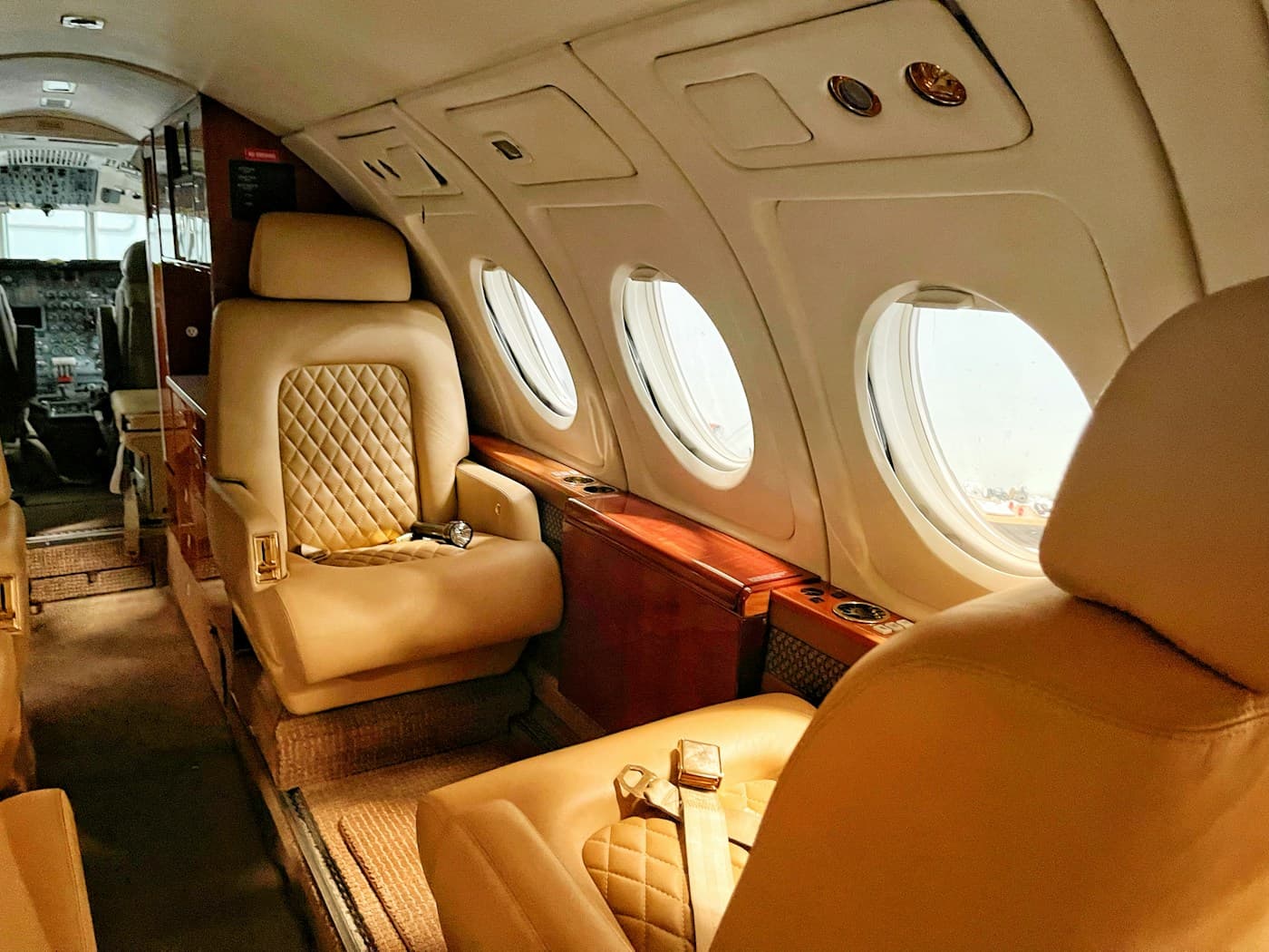 Tan leather cabin of a light jet with oval windows